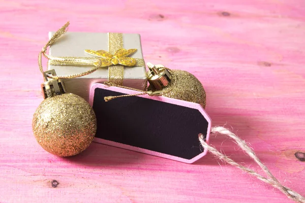 Tarjeta de Navidad con etiqueta, caja de regalo y bolas de Navidad sobre fondo rosa —  Fotos de Stock