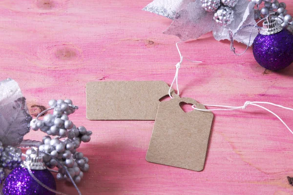 Kerstkaart met label, doos van de gift en kerstballen op roze achtergrond — Stockfoto