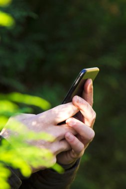 Adam el ile yeşil arka plan üstünde hareket eden telefon