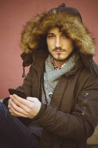 Mladý muž sedí s mobilním telefonem — Stock fotografie