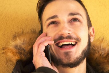 duvar sarı ile desteklenen cep telefonuyla konuşan erkek genç