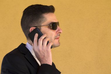 Cep telefonu ile konuşurken takım elbiseli genç adam