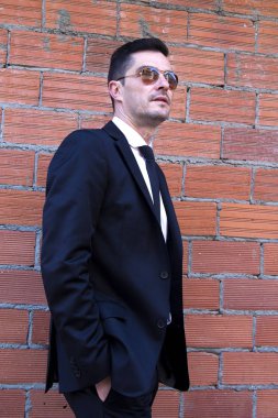 Takım elbiseli, elleri ceplerinde bir adam.