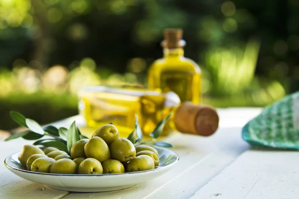 Prato de azeitonas e garrafas de azeite sobre a mesa — Fotografia de Stock