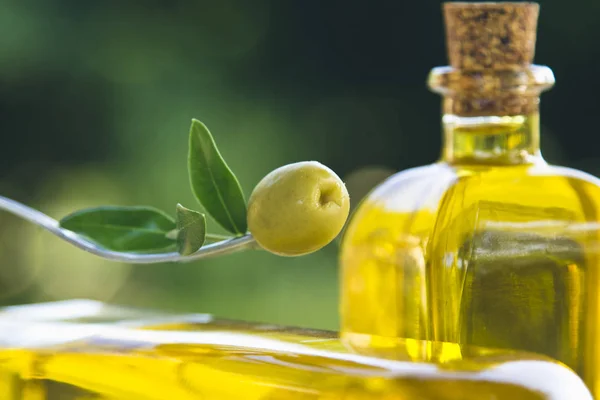 Tenedor con aceituna sobre fondo de botellas de aceite de oliva — Foto de Stock