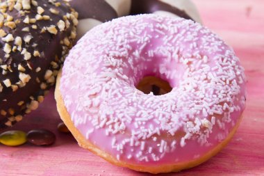 Ürün çeşitliliği ile şeker pembe ahşap arka plan üzerinde renkli donut