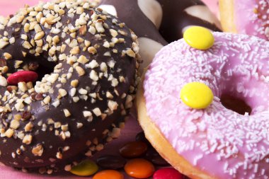 Ürün çeşitliliği ile şeker pembe ahşap arka plan üzerinde renkli donut