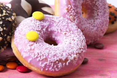 Ürün çeşitliliği ile şeker pembe ahşap arka plan üzerinde renkli donut
