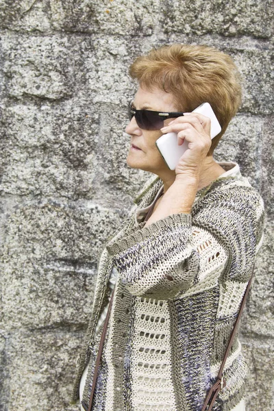 Cep telefonu kullanan yaşlı bir kadın.