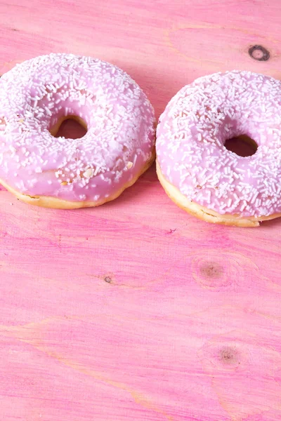 Rosa donuts på rosa trä bakgrund — Stockfoto