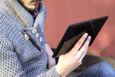 tablet kullanarak parkta oturan genç adam