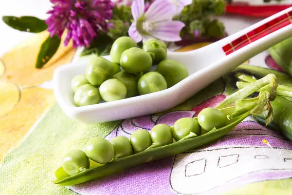Colher de ervilhas verdes na toalha de mesa colorida — Fotografia de Stock