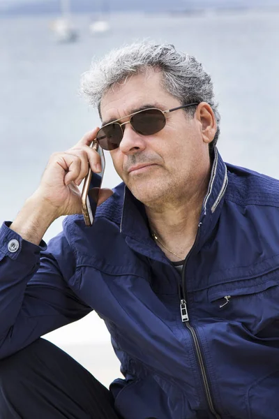 Hombre mayor en la playa hablando con el celular — Foto de Stock