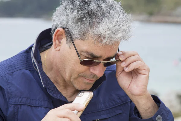 Senior man använder mobiltelefon på stranden — Stockfoto