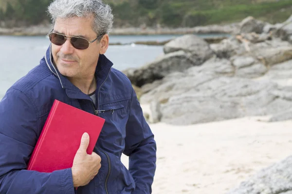 Hombre mayor con un libro en la playa — Foto de Stock