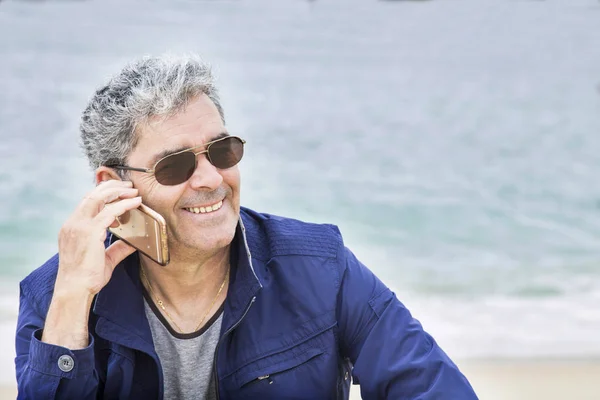 Hombre mayor con un libro en la playa — Foto de Stock