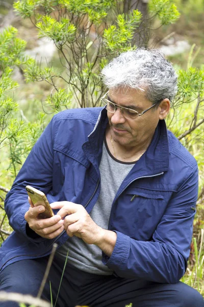 Hombre mayor en la montura usando el teléfono móvil — Foto de Stock