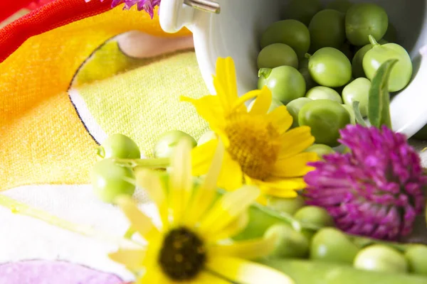 Grüne Erbsen auf Tischdecke mit Blumen — Stockfoto