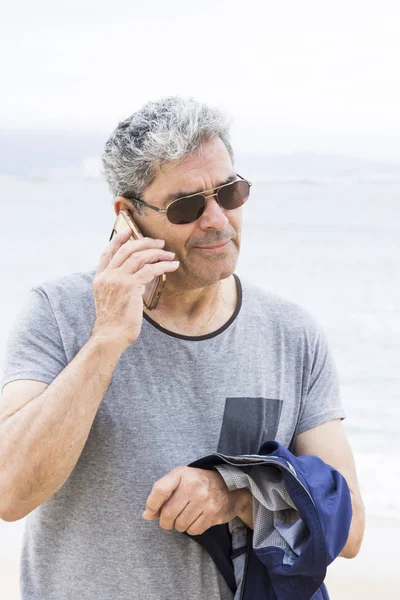 Hombre mayor hablando por teléfono en la playa — Foto de Stock
