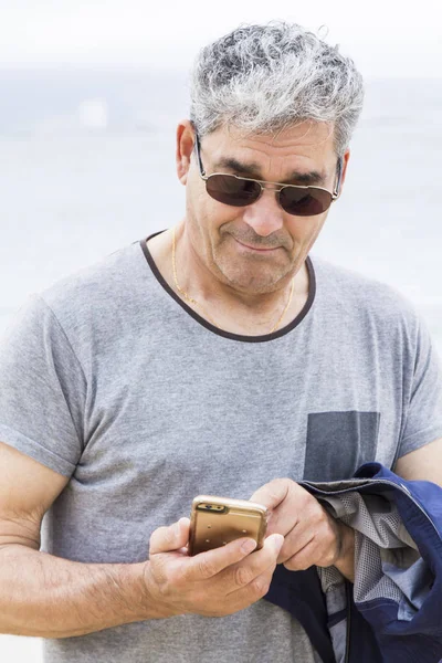 Старший чоловік розмовляє по телефону на пляжі — стокове фото