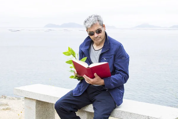 Senior mannen sitter en bok — Stockfoto