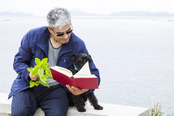Sênior com livro e cachorro — Fotografia de Stock
