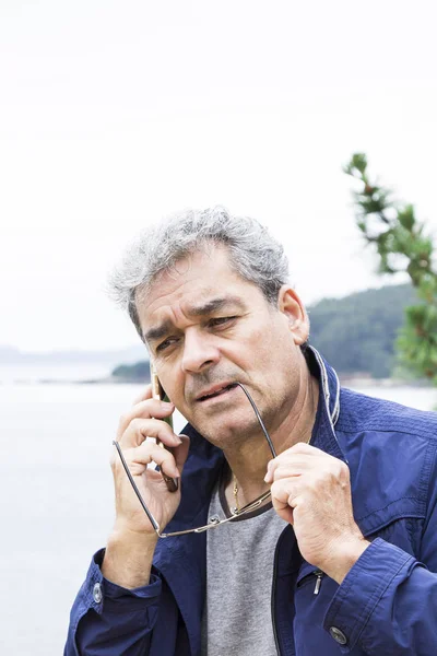 Senior man pratar i telefon på stranden — Stockfoto