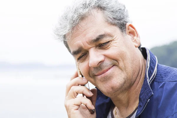 年配の男性がビーチで電話で話しています。 — ストック写真