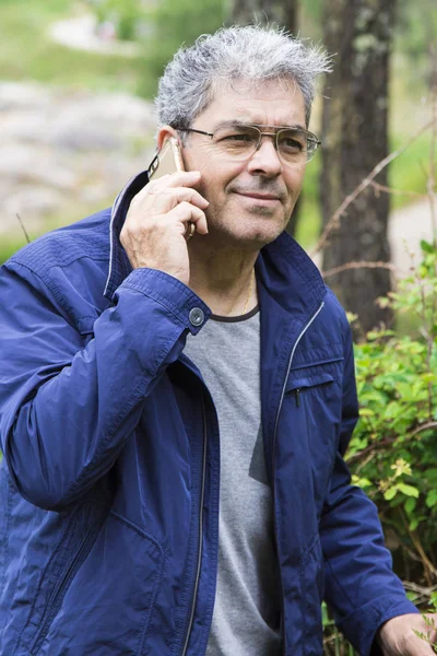 Hombre mayor hablando por celular en el bosque — Foto de Stock