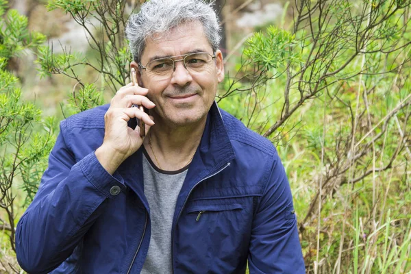 Hombre mayor hablando por celular en el bosque — Foto de Stock