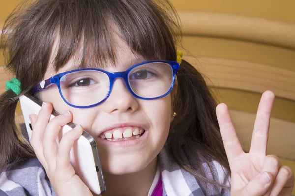 little girl talking on the mobile phone and making a symbol of ok