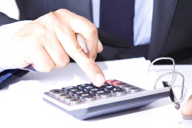 Ofiste hesap makinesi olan bir iş adamı var.