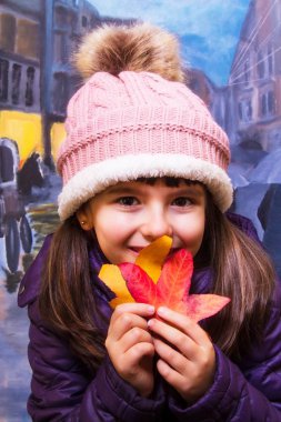 sonbaharda ağaç yaprakları ile oynarken küçük kız