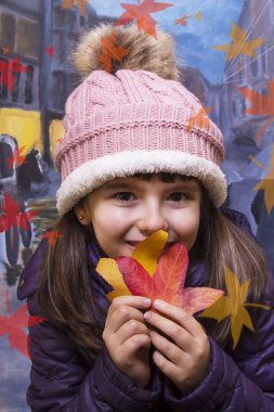 sonbaharda ağaç yaprakları ile oynarken küçük kız