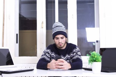 Cep telefonu kullaranarak ofisinde oturan genç adam