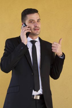 Ok işareti yapmak ve cep telefonu ile konuşurken takım elbiseli adam