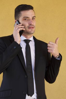 Ok işareti yapmak ve cep telefonu ile konuşurken takım elbiseli adam