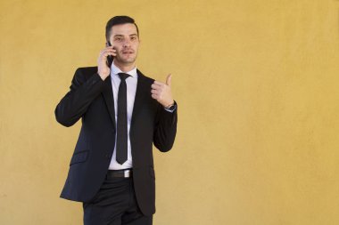 Ok işareti yapmak ve cep telefonu ile konuşurken takım elbiseli adam