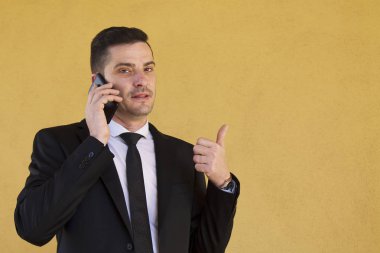 Ok işareti yapmak ve cep telefonu ile konuşurken takım elbiseli adam