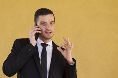 Ok işareti yapmak ve cep telefonu ile konuşurken takım elbiseli adam