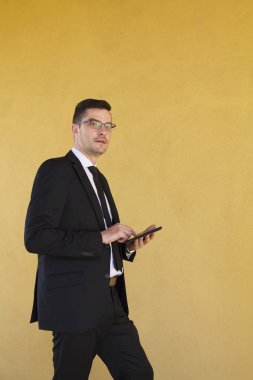 Sarı duvar arka plan ile tablet ile işadamı