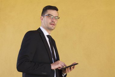 Sarı duvar arka plan ile tablet ile işadamı