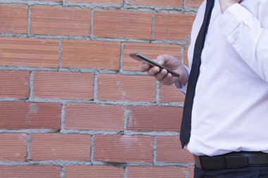 Erkek takım elbise ve cep telefonuyla tuğla zemin üzerine güneş gözlüğü