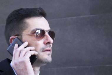 Erkek takım elbise ve cep telefonu için konuşmaya güneş gözlüğü