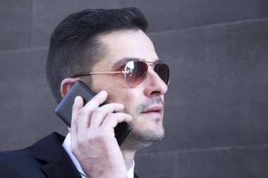 Erkek takım elbise ve cep telefonu için konuşmaya güneş gözlüğü