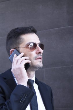 Erkek takım elbise ve cep telefonu için konuşmaya güneş gözlüğü