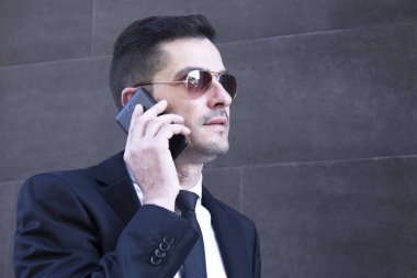 Erkek takım elbise ve cep telefonu için konuşmaya güneş gözlüğü