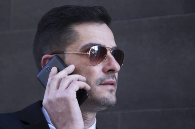 Erkek takım elbise ve cep telefonda konuşurken güneş gözlüğü