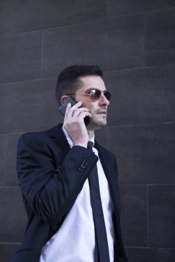 Erkek takım elbise ve cep telefonda konuşurken güneş gözlüğü