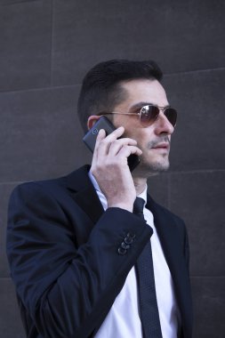 Erkek takım elbise ve cep telefonda konuşurken güneş gözlüğü